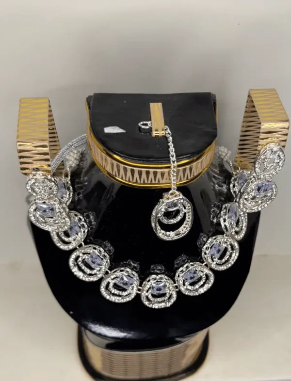 A silver and diamond necklace with circular pendants displayed on a black and gold decorative stand against a light background.