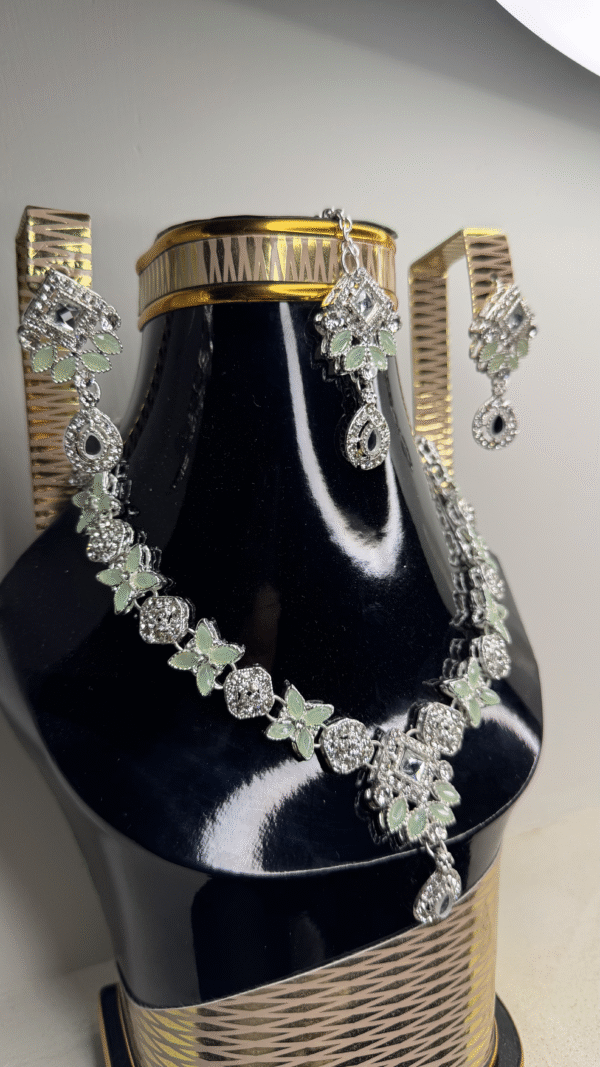 A zircon necklace and earrings displayed on a black mannequin, showcasing their elegant design and sparkling details.