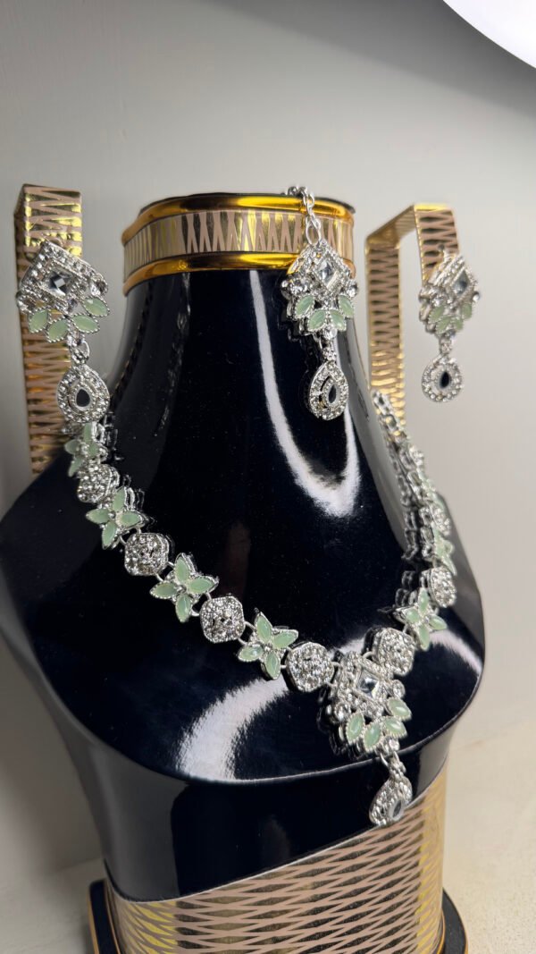 A zircon necklace and earrings displayed on a black mannequin, showcasing their elegant design and sparkling details.